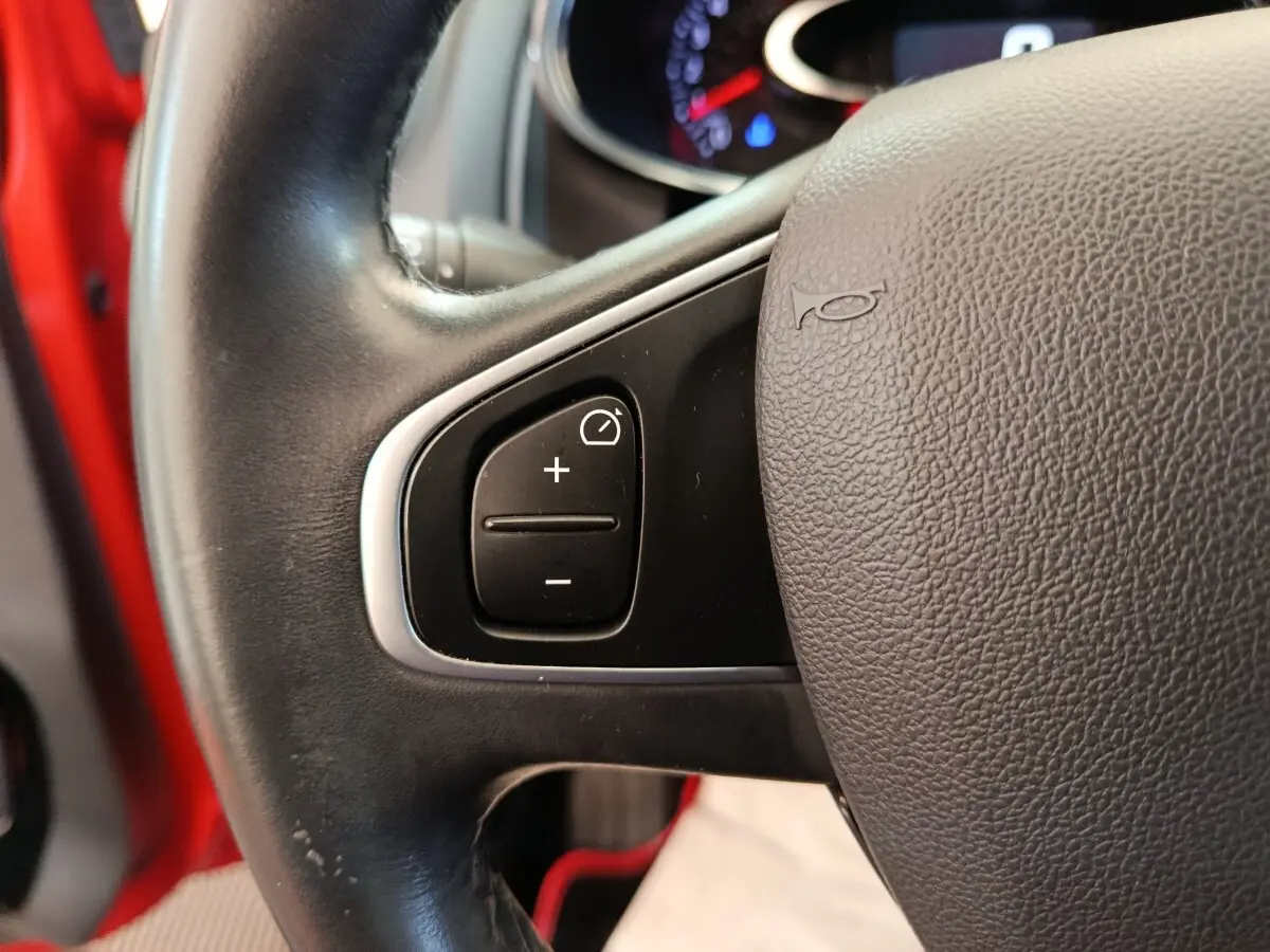 Gros plan sur le volant cuir côté gauche de la Renault Clio rouge 2018 avec commandes de régulateur de vitesse.