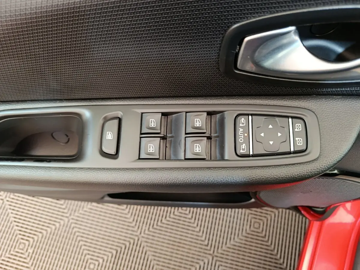 Vue rapprochée de la commande des vitres et rétroviseurs sur la porte côté conducteur d’une Renault Clio rouge 2018.