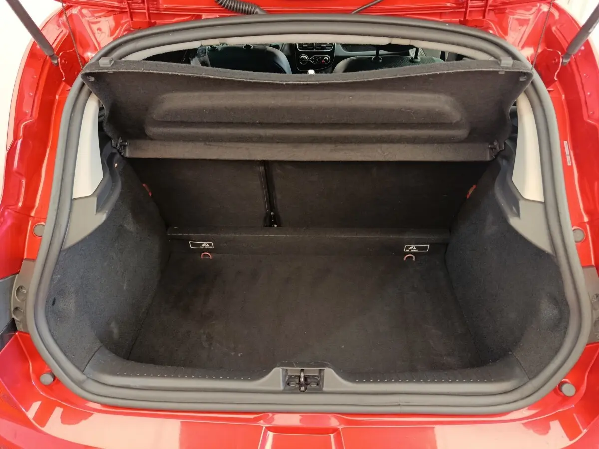 Coffre ouvert vu de l'arrière d'une Renault Clio Intens Energy TCe 90 rouge, intérieur noir et tablette de coffre relevée.