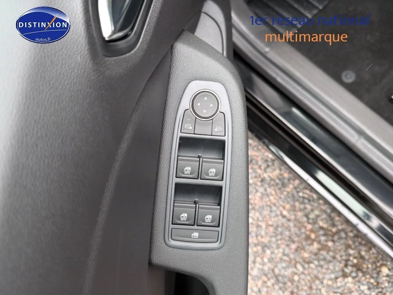 Gros plan sur les commandes des vitres électriques et rétroviseurs côté gauche de la porte d’une Renault Clio V noire.