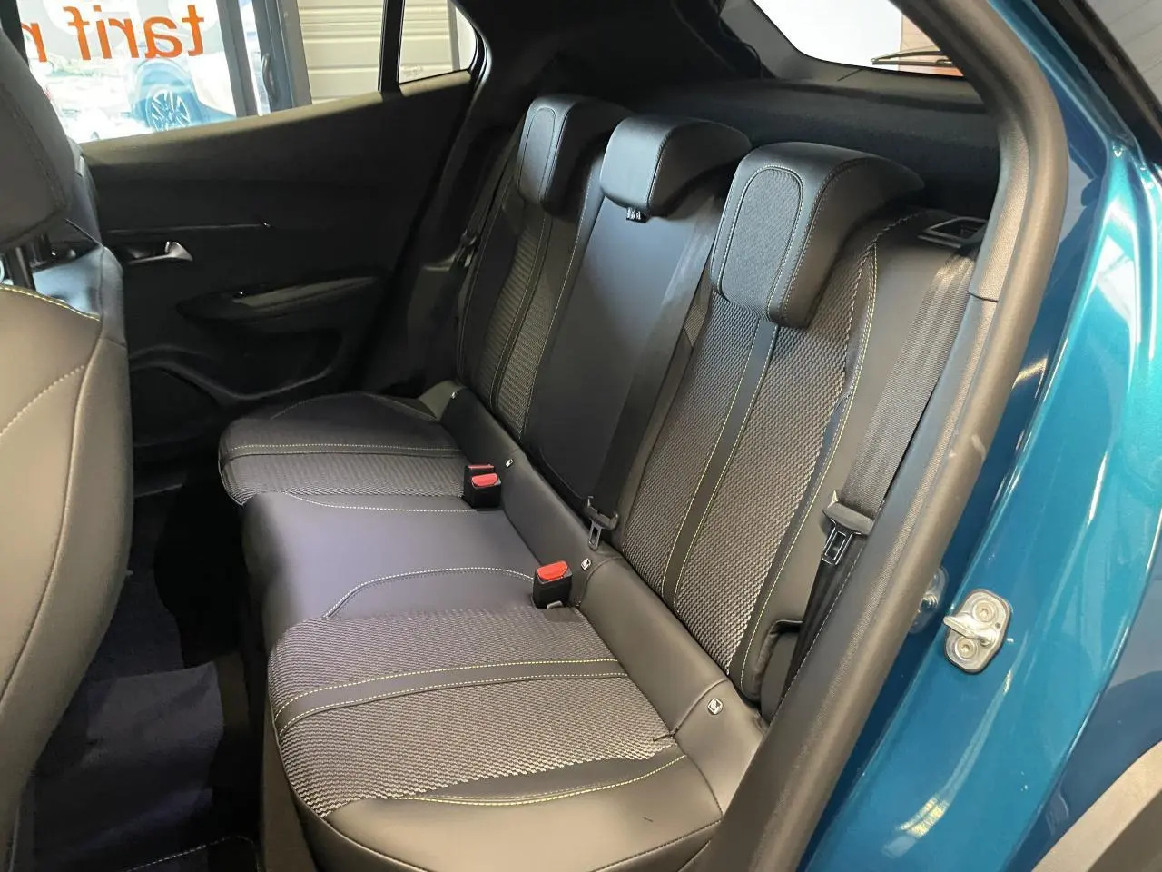 Banquette arrière en tissu et cuir noir avec surpiqûres vertes, vue côté droit porte ouverte d’un Peugeot 2008 bleu.