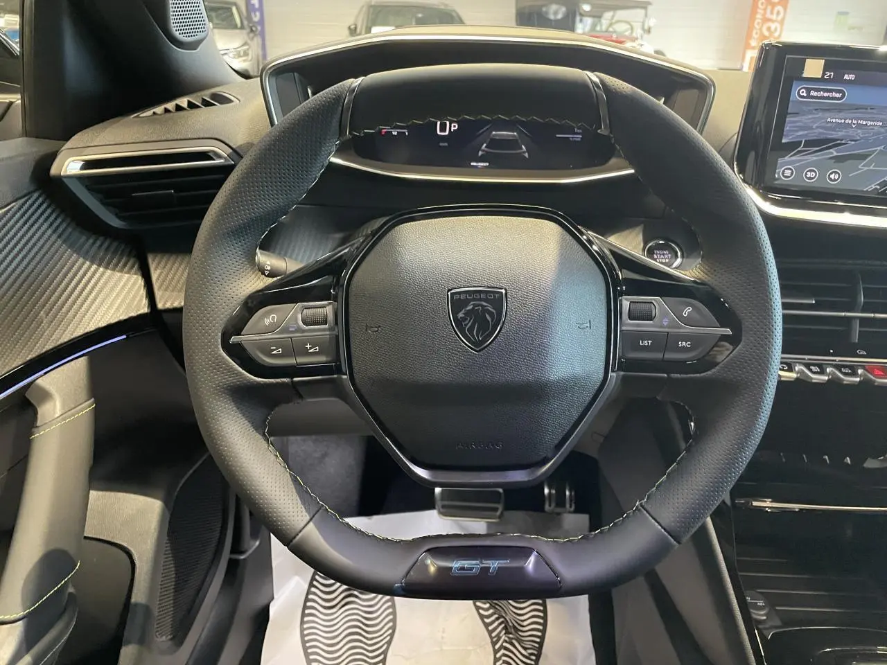 Vue intérieure centrée sur le volant GT noir perforé du Peugeot 2008 1.2i Hybrid avec tableau de bord numérique.