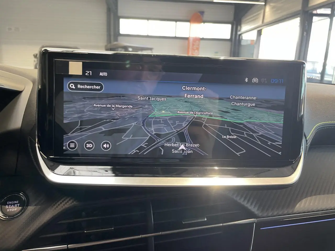 Vue intérieure centrée sur l'écran tactile de navigation 3D du Peugeot 2008 hybride, avec tableau de bord noir et surpiqûres jaunes.
