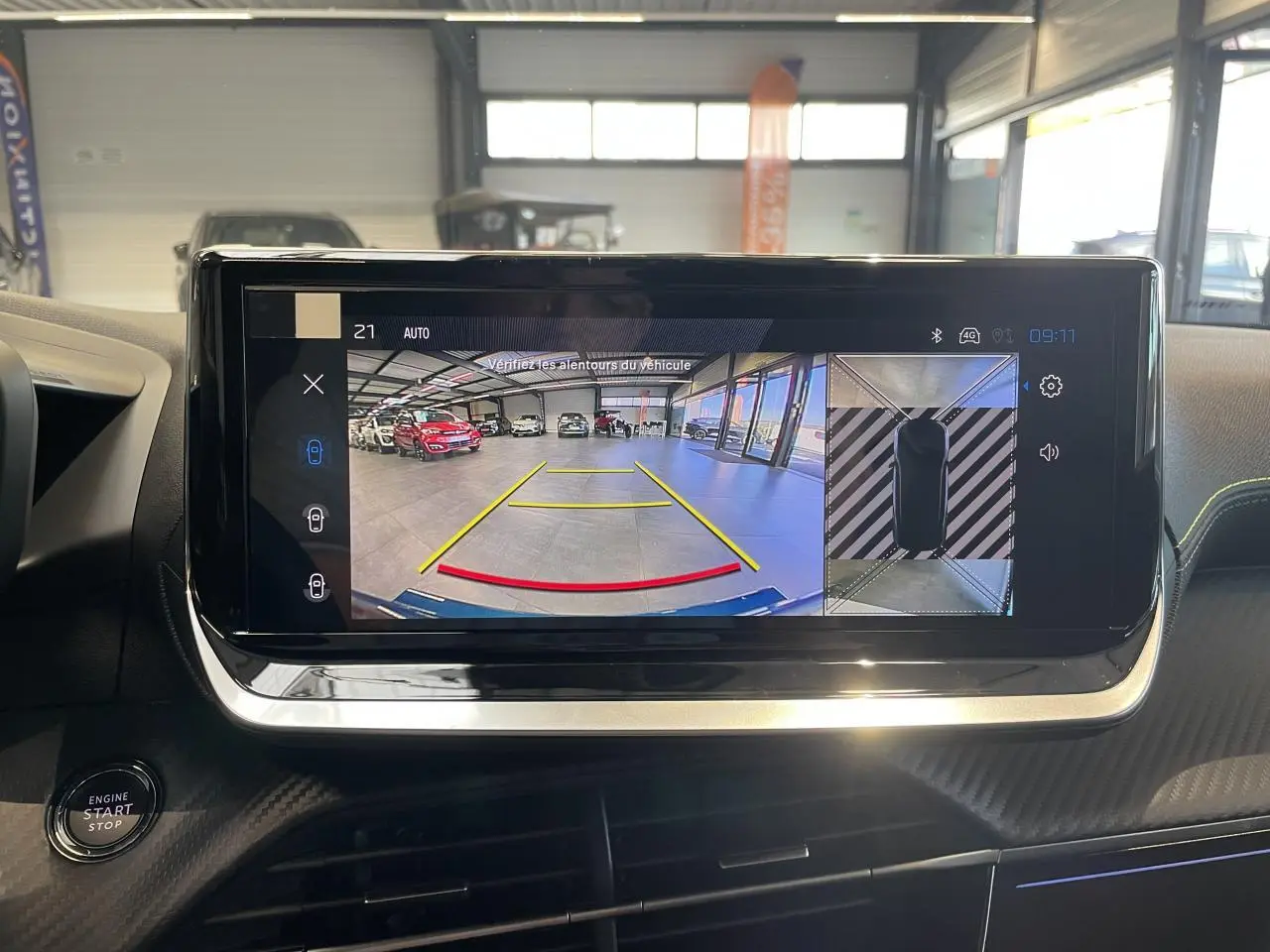 Écran tactile intérieur du Peugeot 2008 bleu montrant la caméra de recul et vue à 360° en stationnement.
