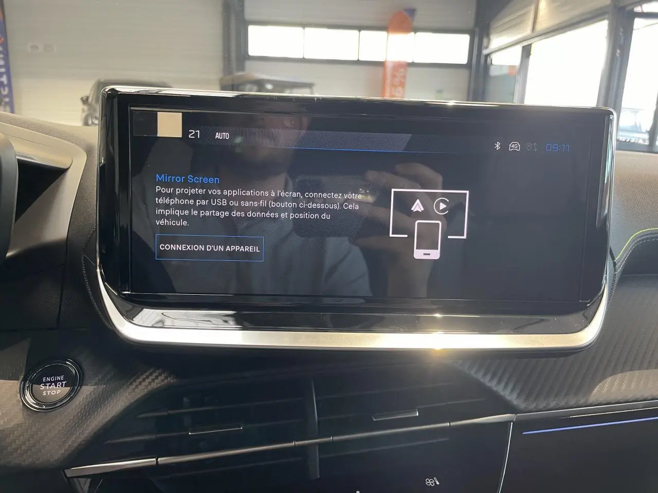 Écran tactile central en gros plan dans l’habitacle noir du Peugeot 2008 bleu, avec bouton démarrage visible à gauche.