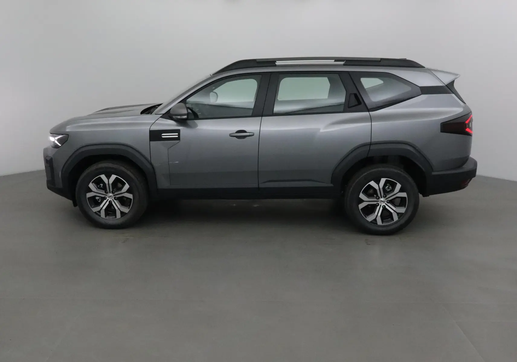 Profil côté gauche du SUV Dacia Bigster gris schiste 2025 avec jantes alliage et toit noir contrasté.