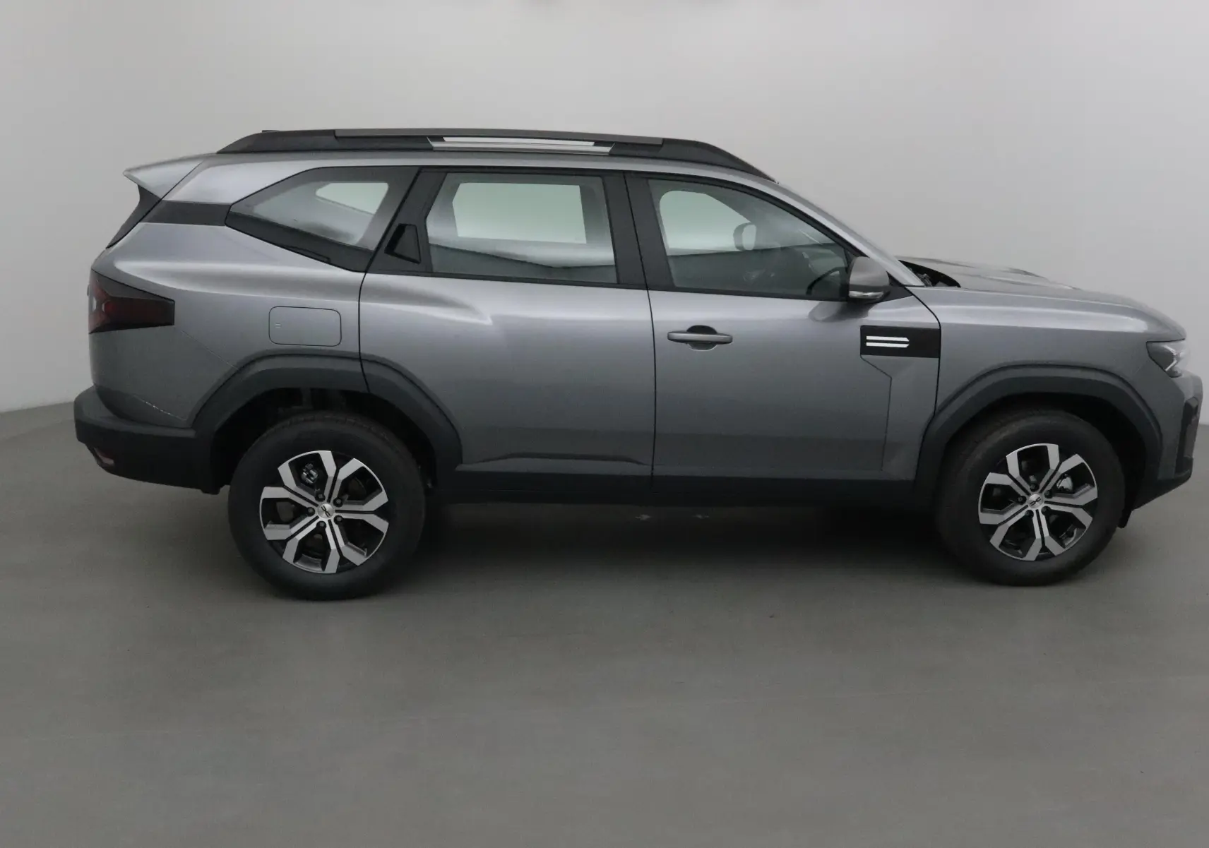 Profil droit du SUV Dacia Bigster gris schiste avec lignes anguleuses et jantes alliage noires et argentées.