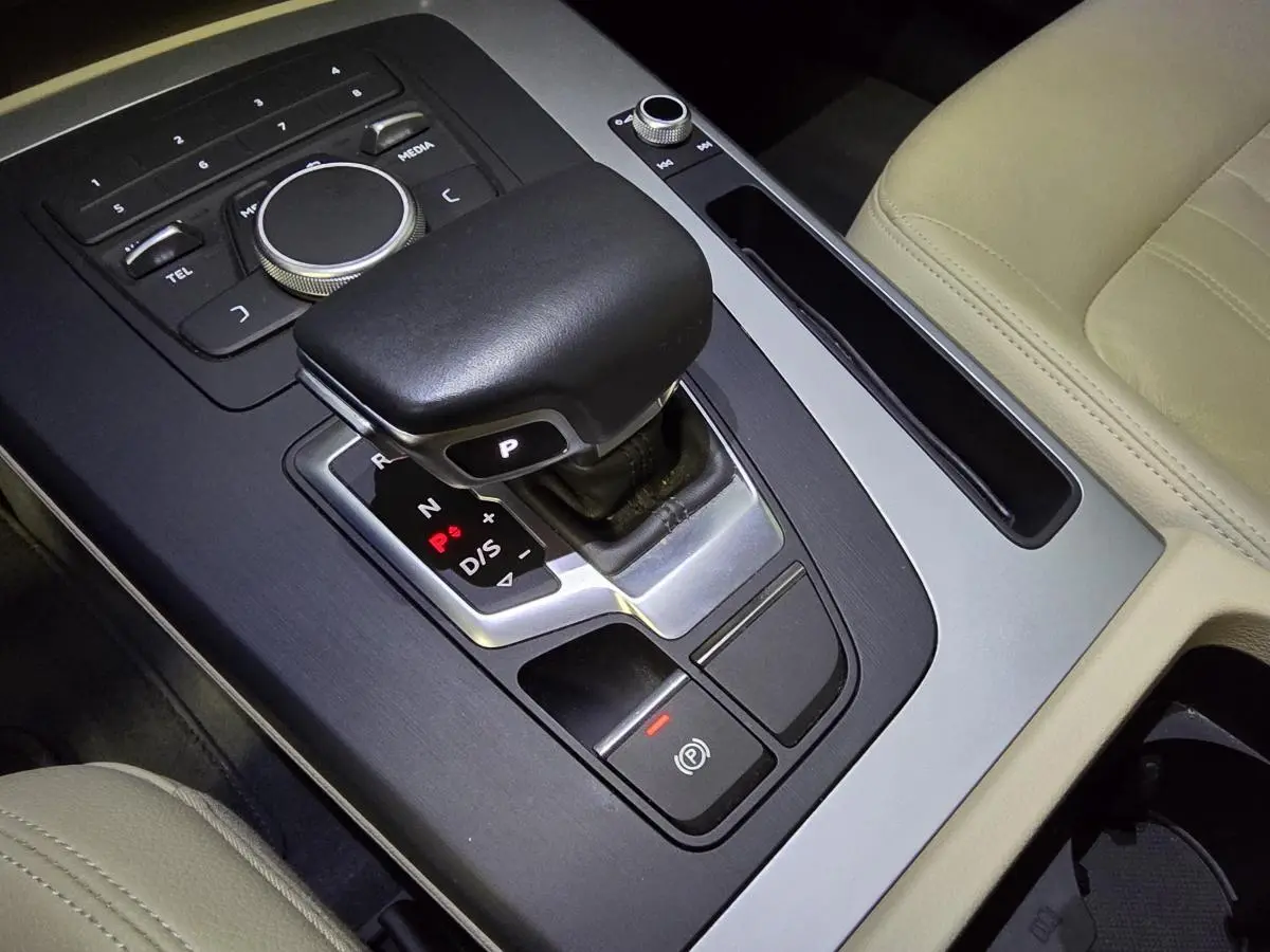 Gros plan sur la console centrale beige de l'Audi Q5 2019 avec levier de vitesse automatique et commandes multimédia.