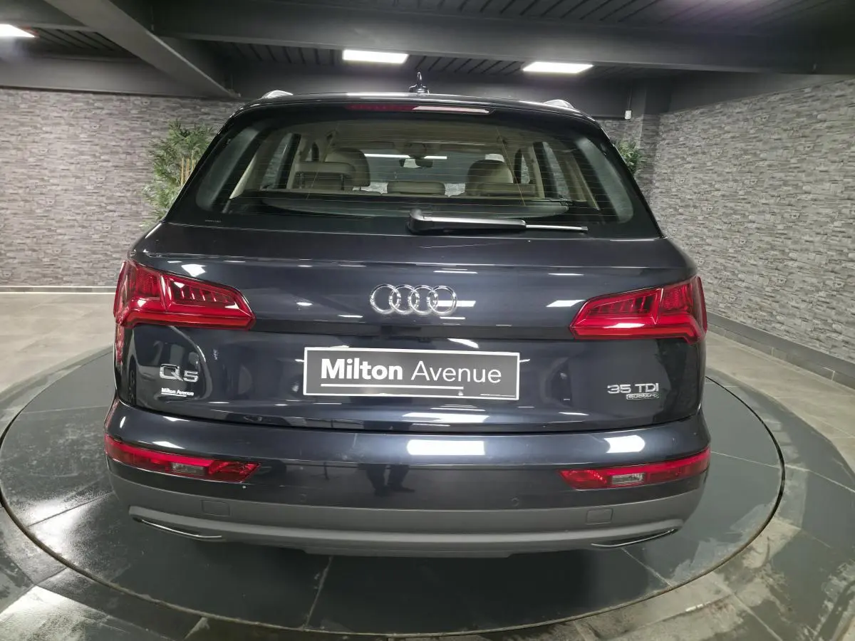 Vue arrière d'un Audi Q5 bleu métallisé avec badges 35 TDI quattro et plaque Milton Avenue dans un garage.