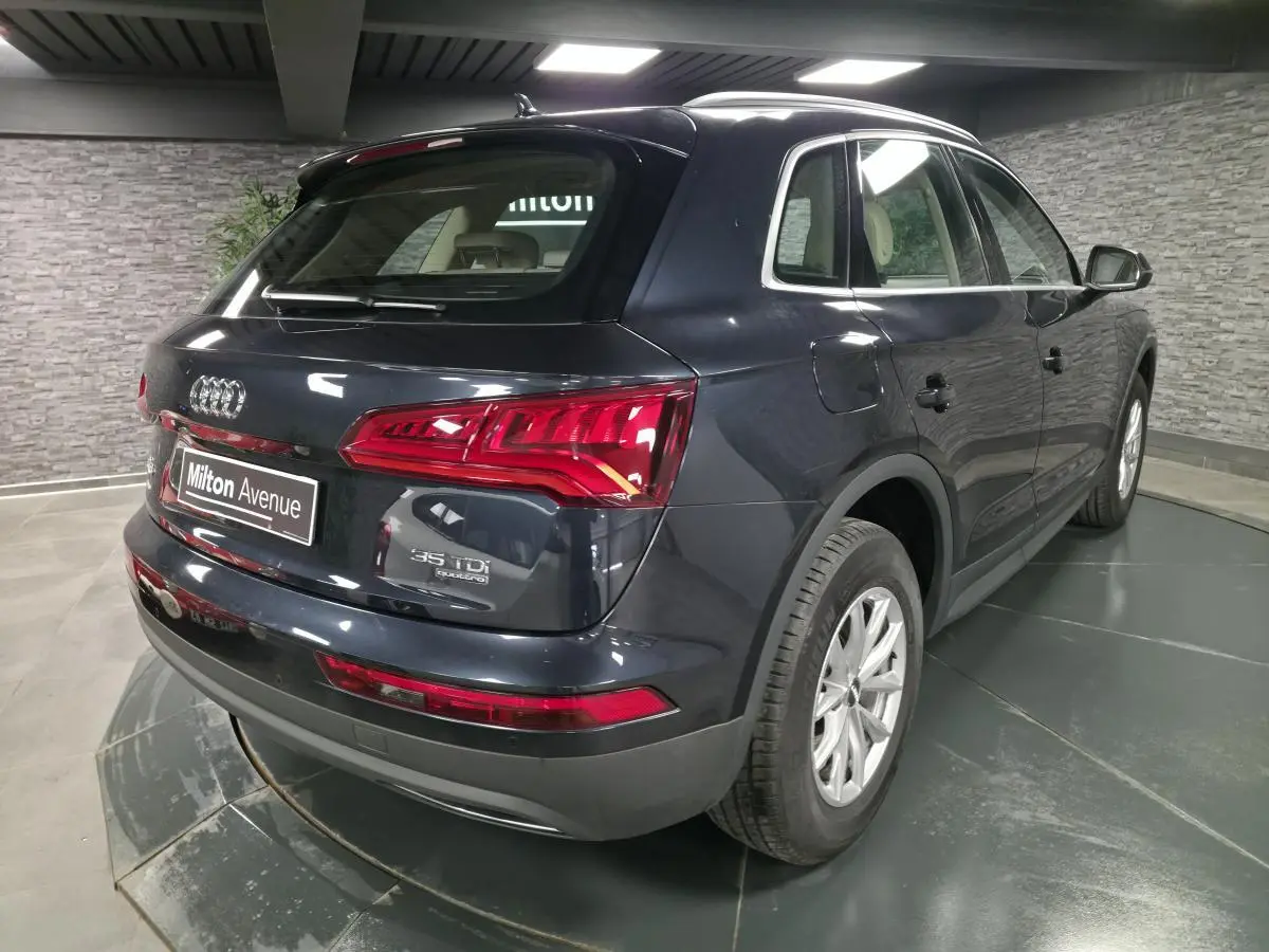 Audi Q5 bleu métallisé vu en 3/4 arrière droit, avec feux arrière LED et jantes aluminium 17 pouces.