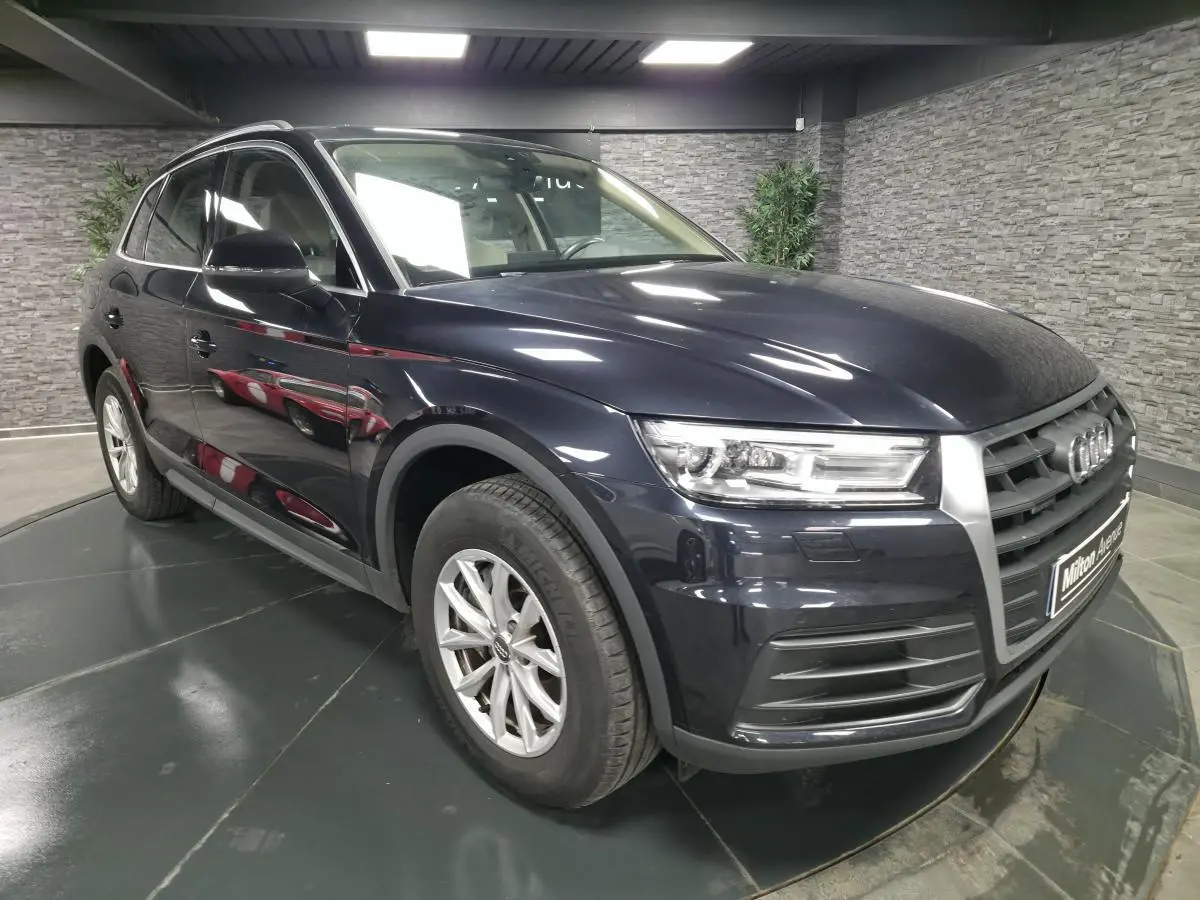 Audi Q5 bleu métallisé en 3/4 avant droit, avec calandre imposante et jantes alliage 17 pouces visibles.