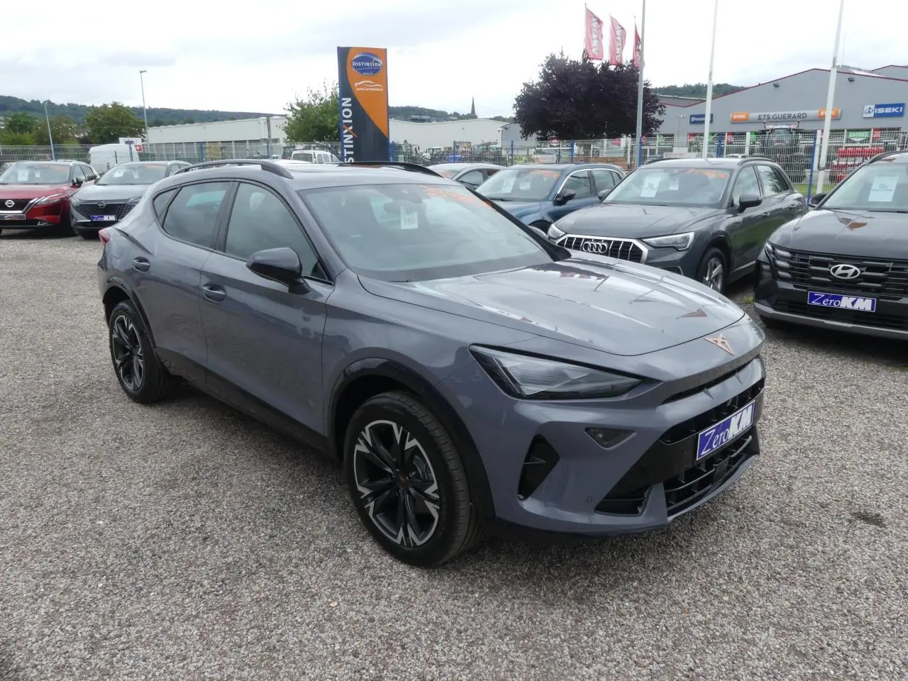 CUPRA Formentor gris Graphène en 3/4 avant avec coques de rétroviseurs noires sur parking extérieur.