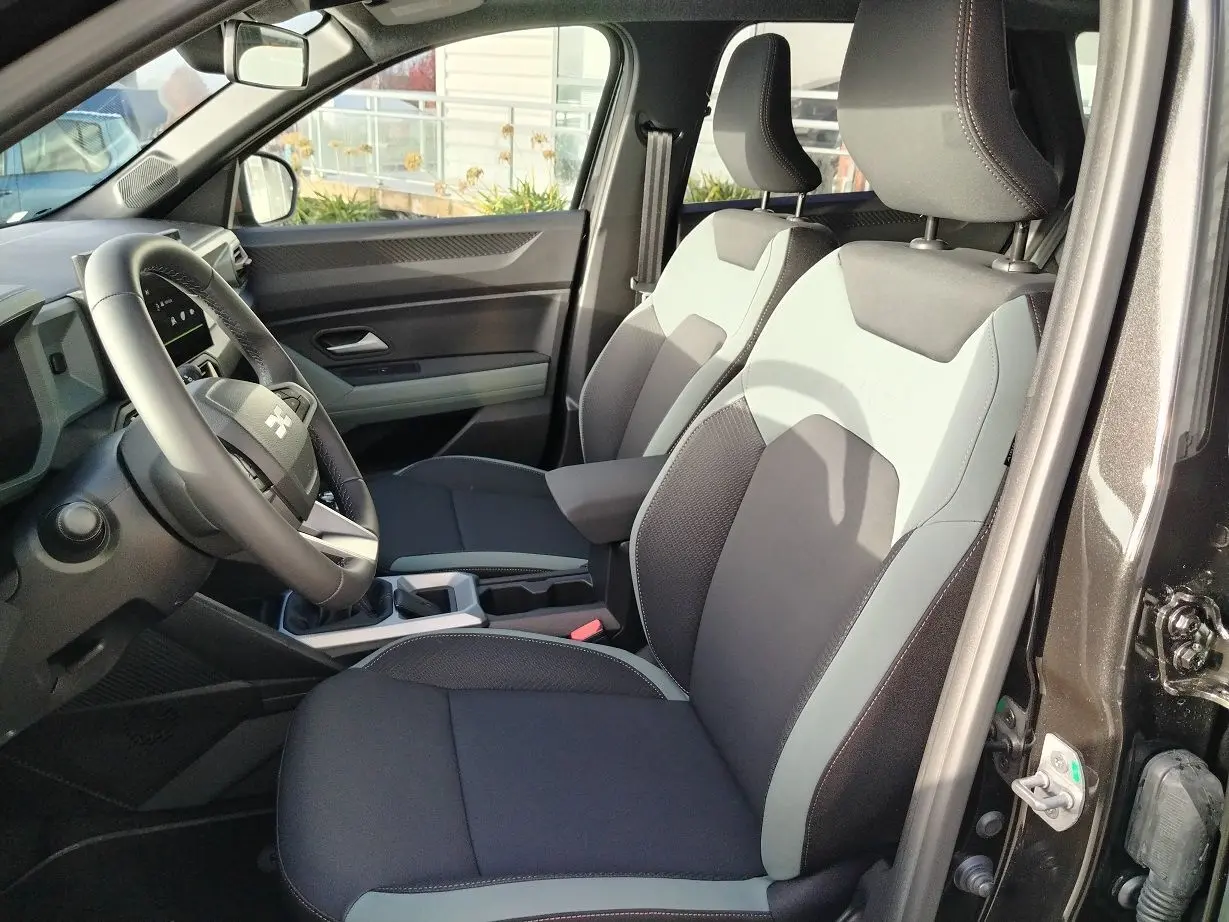 Vue intérieure côté conducteur du Dacia Bigster 2025 noir, montrant les sièges bi-ton et le volant multifonction.