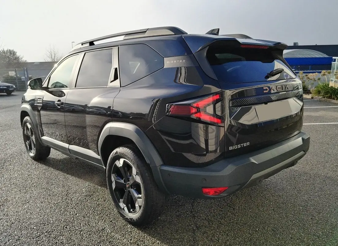 Vue 3/4 arrière droite du SUV noir Dacia Bigster 2025 avec jantes noires et feux arrière en forme de flèche.