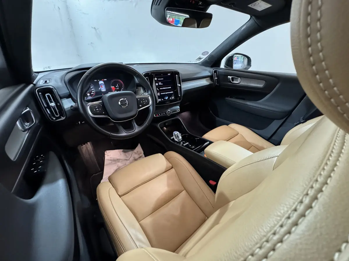 Intérieur du Volvo XC40 Recharge T5 2021 vu côté conducteur, sièges cuir beige et tableau de bord noir avec écran tactile central.