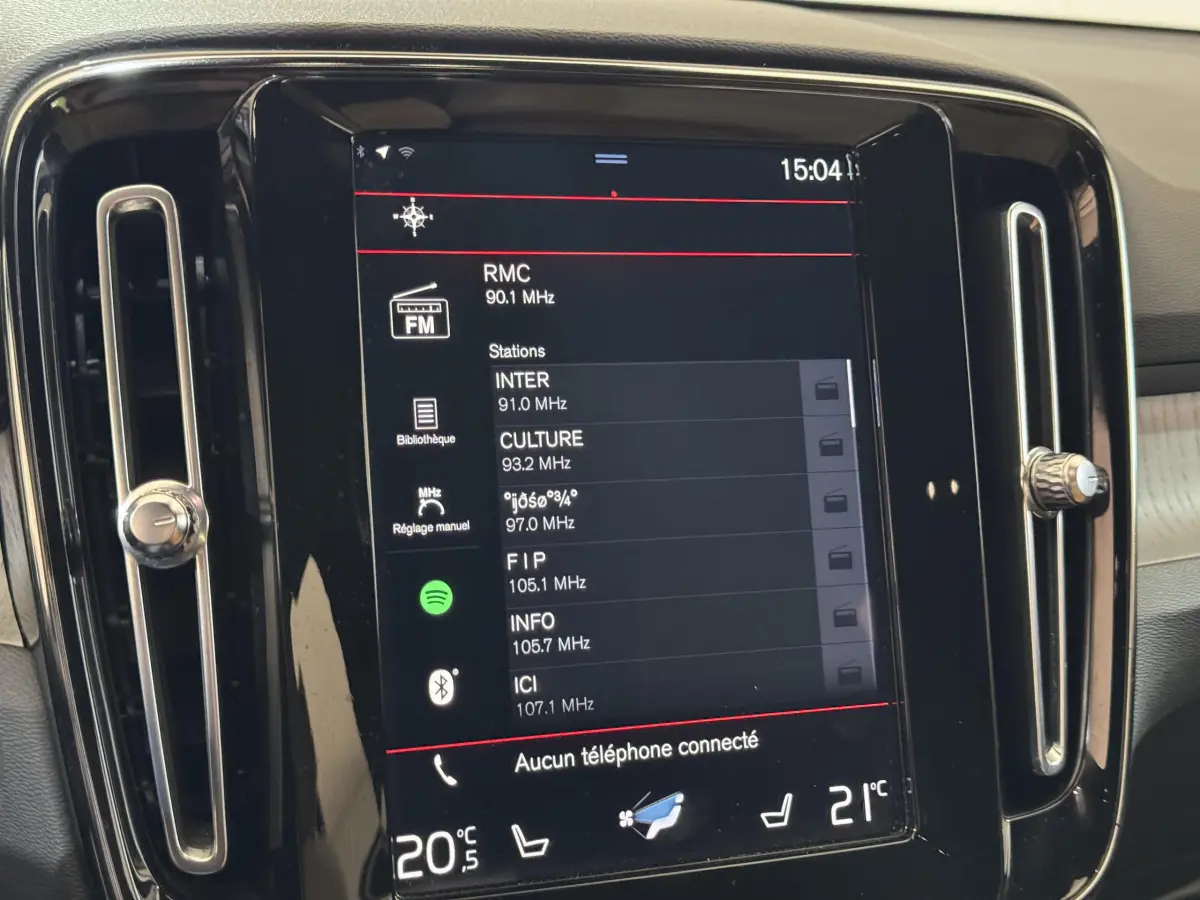 Écran tactile central du tableau de bord du Volvo XC40 Recharge T5 noir, affichant les stations radio FM.