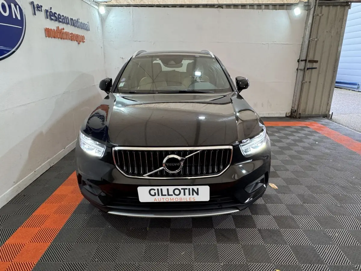 Vue frontale d'un Volvo XC40 Recharge T5 noir avec phares LED allumés dans un showroom.