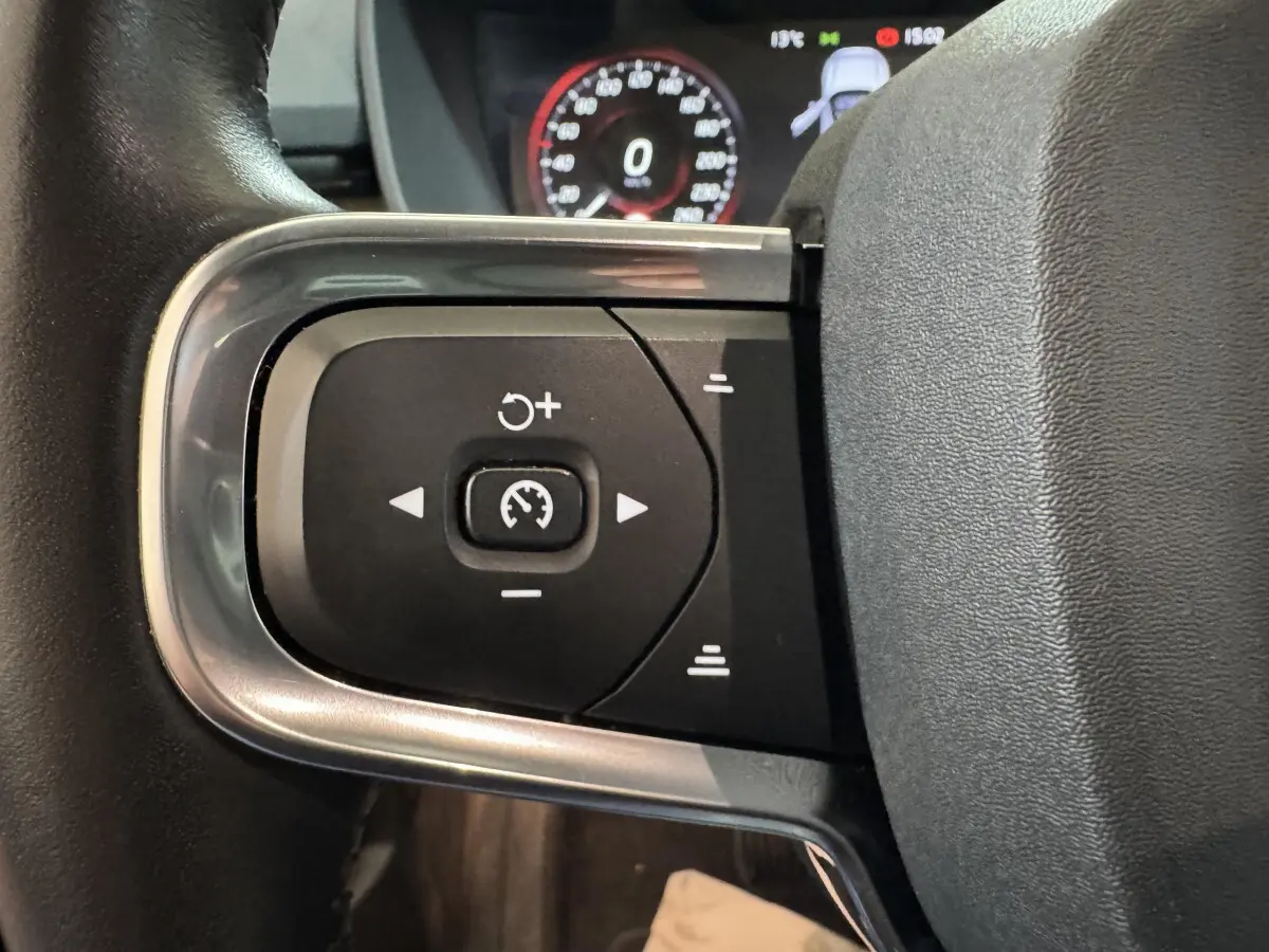 Gros plan sur les commandes de régulateur de vitesse au volant cuir du Volvo XC40 Recharge T5 noir de 2021.