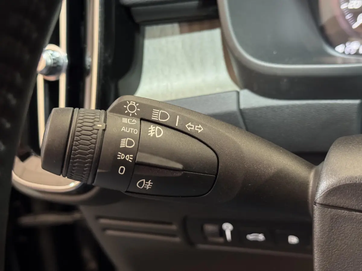Gros plan sur la commande des phares et clignotants à gauche du volant dans un Volvo XC40 noir de 2021.