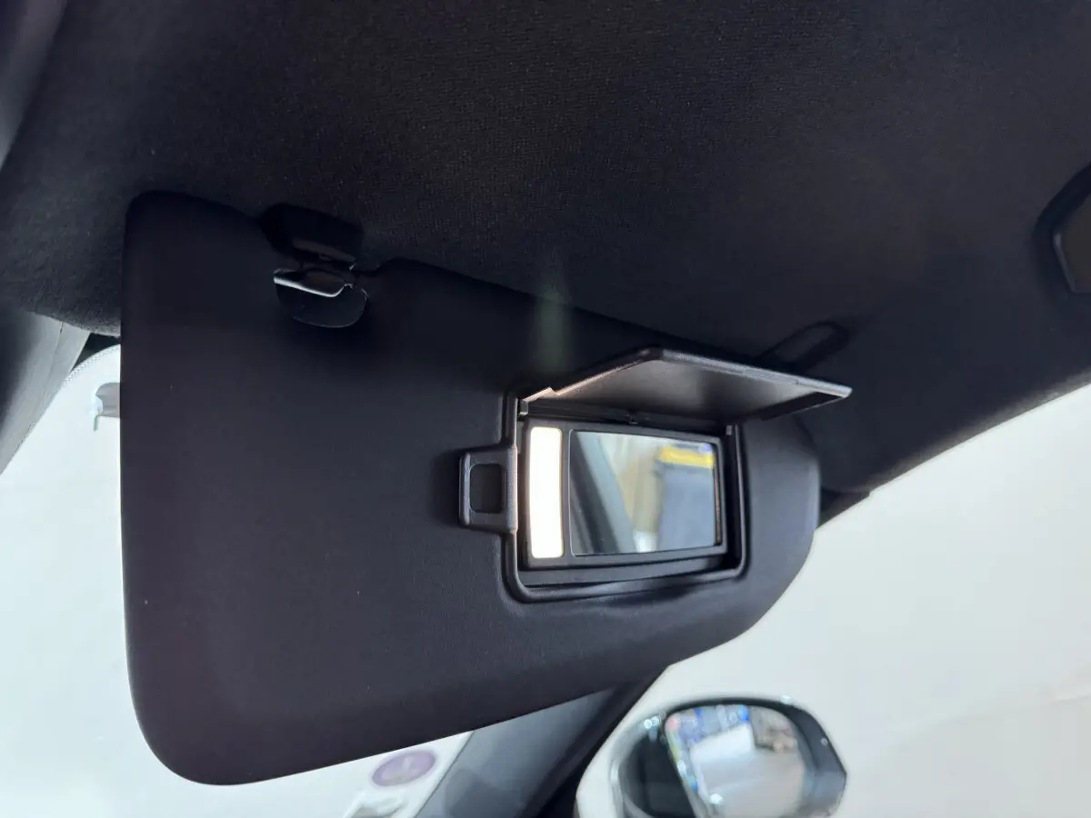 Miroir de courtoisie ouvert sur le pare-soleil côté conducteur dans l'habitacle noir du Volvo XC40 Recharge T5.