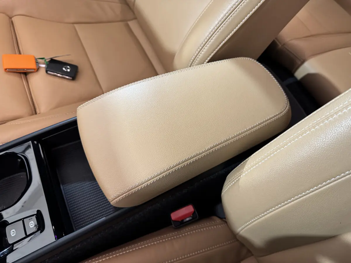 Accoudoir central beige en cuir vu de dessus dans l'habitacle du Volvo XC40 Recharge T5 noir avec clés posées sur le siège.