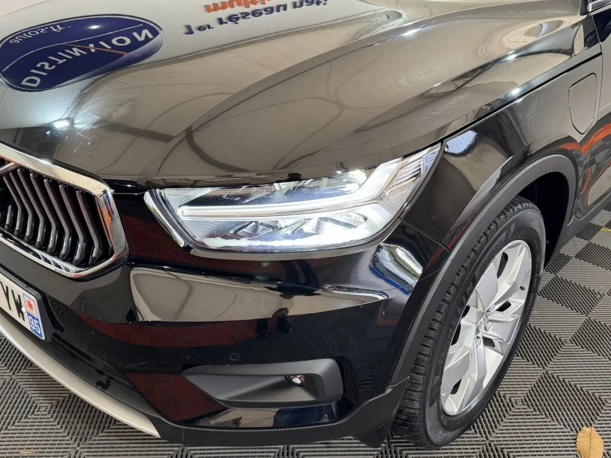 Gros plan sur l'avant droit noir brillant du Volvo XC40 Recharge T5 avec phares LED et jante alu visible.