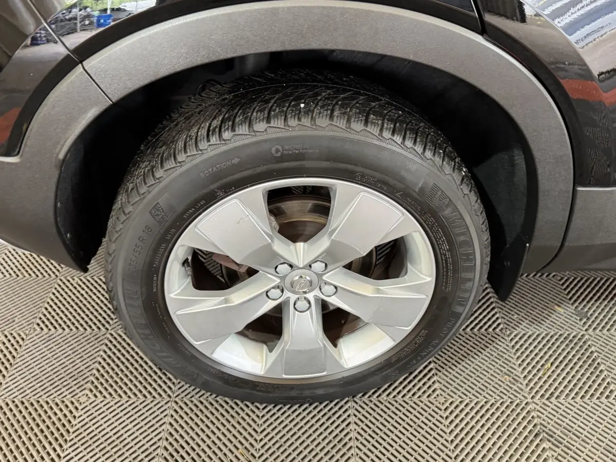 Gros plan sur la roue avant gauche avec jante argentée du Volvo XC40 noir Recharge T5 262 DCT7 Inscription 2021.