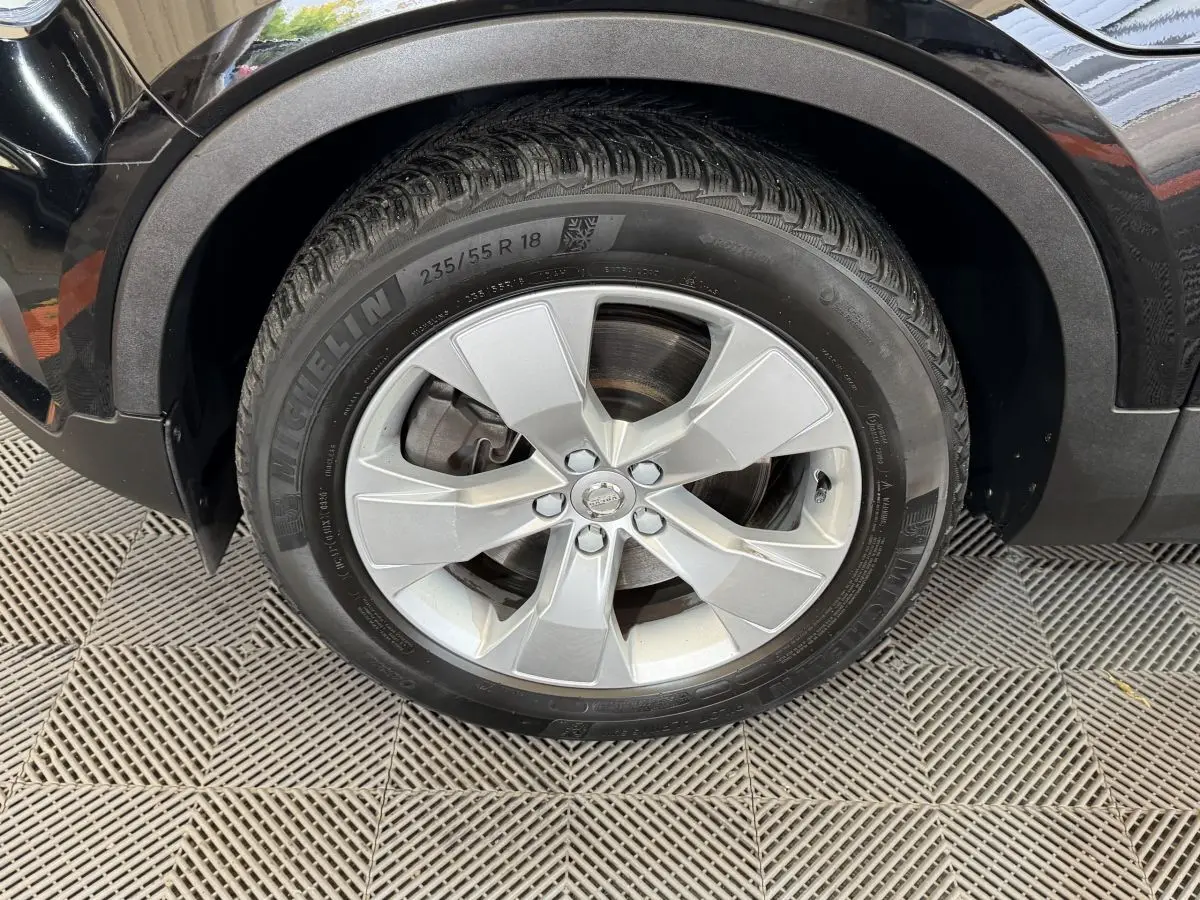 Gros plan sur la roue avant gauche avec jante argentée du Volvo XC40 noir Recharge T5 262 DCT7 Inscription 2021.