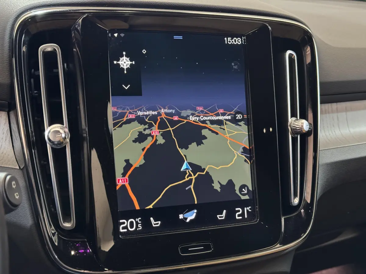 Écran tactile central du tableau de bord du Volvo XC40 noir, affichant la navigation et la climatisation.