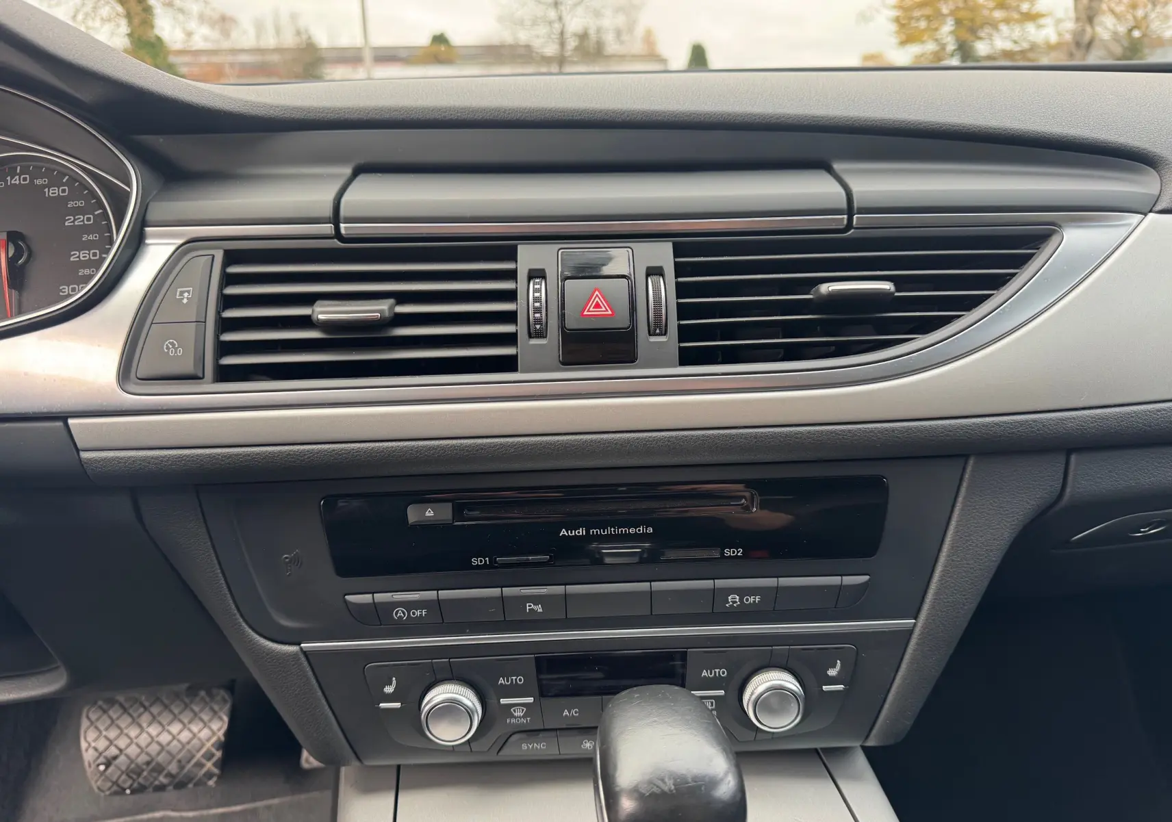 Tableau de bord de l'Audi A6 Avant 2015 noir, vue centrée sur la console avec commandes climatisation et multimédia.