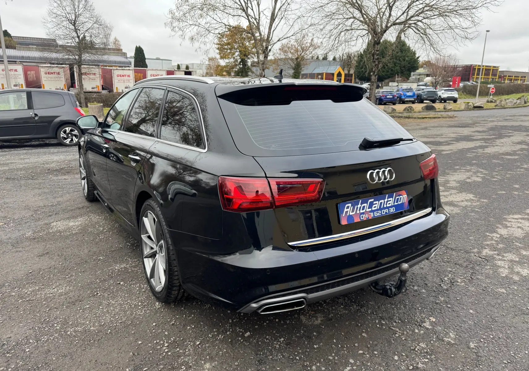 Audi A6 Avant noir vue 3/4 arrière droit, avec attelage et feux arrière LED visibles.