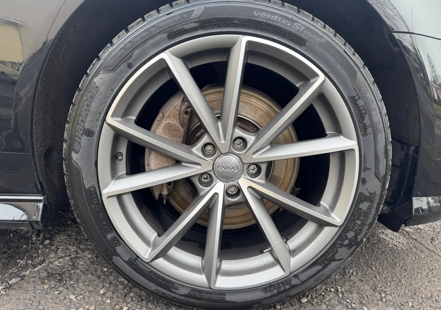 Gros plan sur la roue avant droite d’une Audi A6 Avant noire de 2015 avec jante alliage 19 pouces à dix branches.