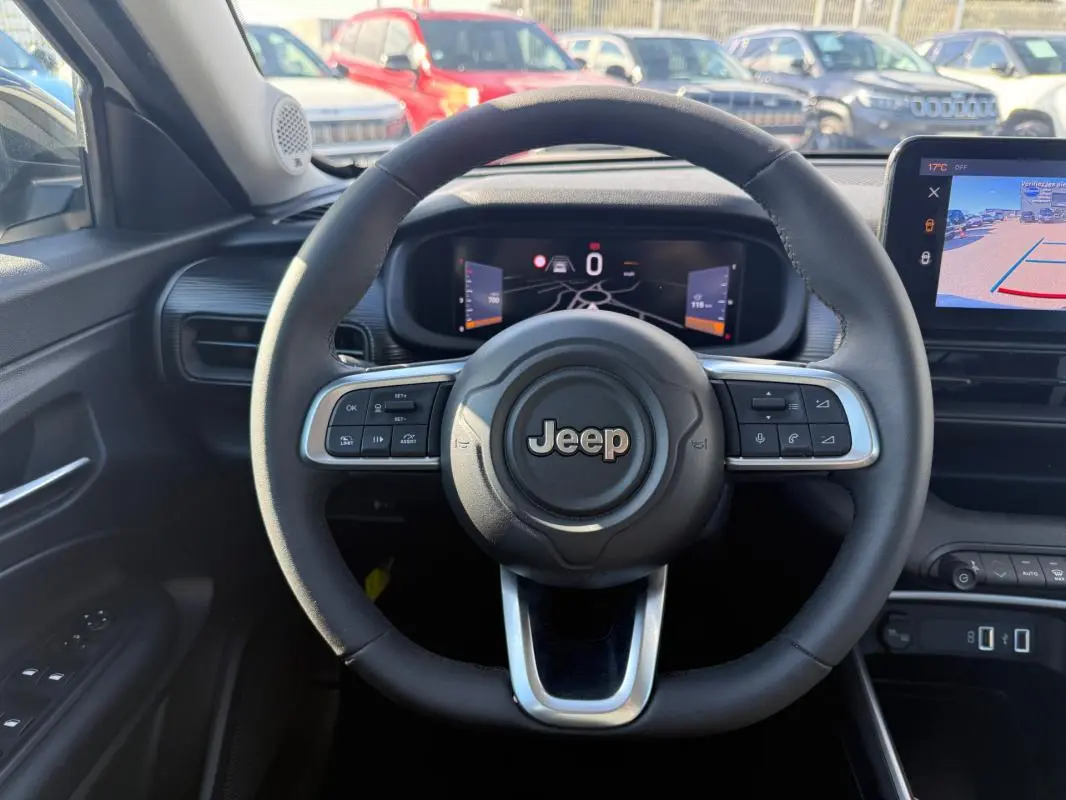 Vue intérieure centrée sur le volant Jeep noir avec tableau de bord numérique et écran multimédia affichant la caméra de recul.