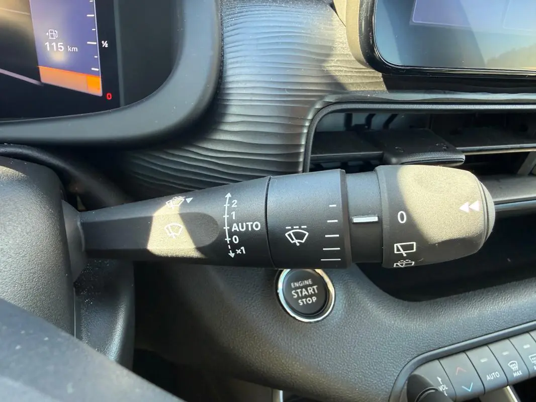 Gros plan sur la commande d’essuie-glace du Jeep Avenger blanc 2025, avec bouton démarrage et tableau de bord partiel.