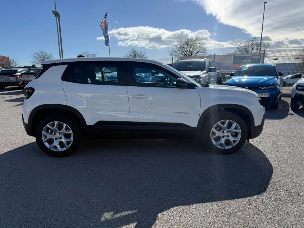 Vue de profil côté gauche d’un Jeep Avenger blanc avec jantes alliage 17 pouces sur parking extérieur.
