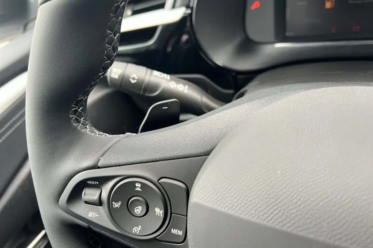 Gros plan sur le volant cuir noir de l’Opel Corsa Hybrid 2026, avec commandes multifonctions et bouton de chauffage.