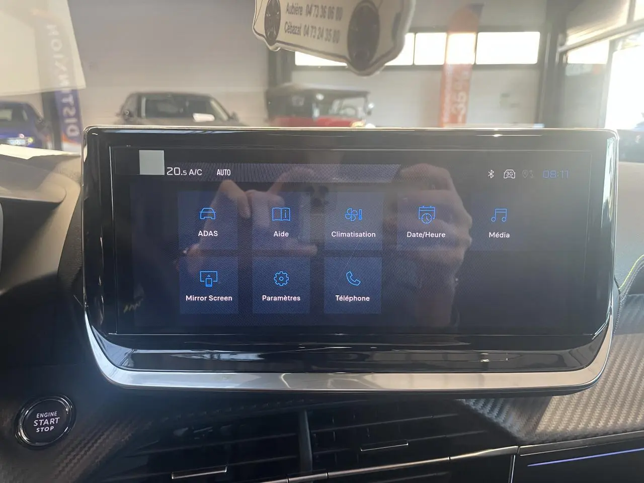 Écran tactile central du Peugeot 2008 1.2i Hybrid 2026 affichant les menus ADAS, climatisation et multimédia, intérieur noir.