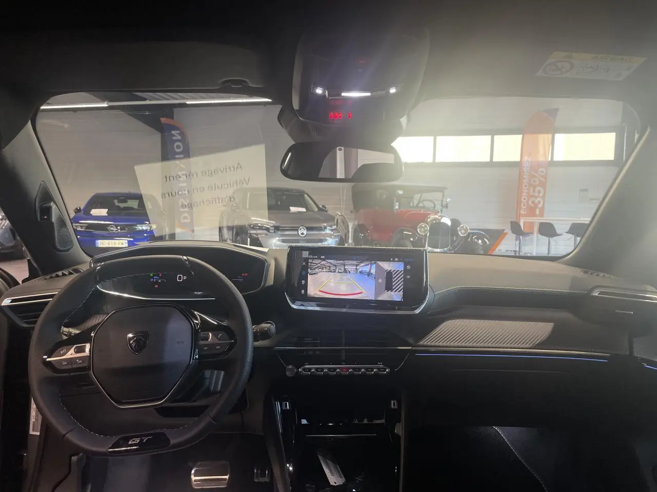 Vue intérieure avant du Peugeot 2008 gris 2026, avec tableau de bord numérique et écran tactile affichant la caméra de recul.