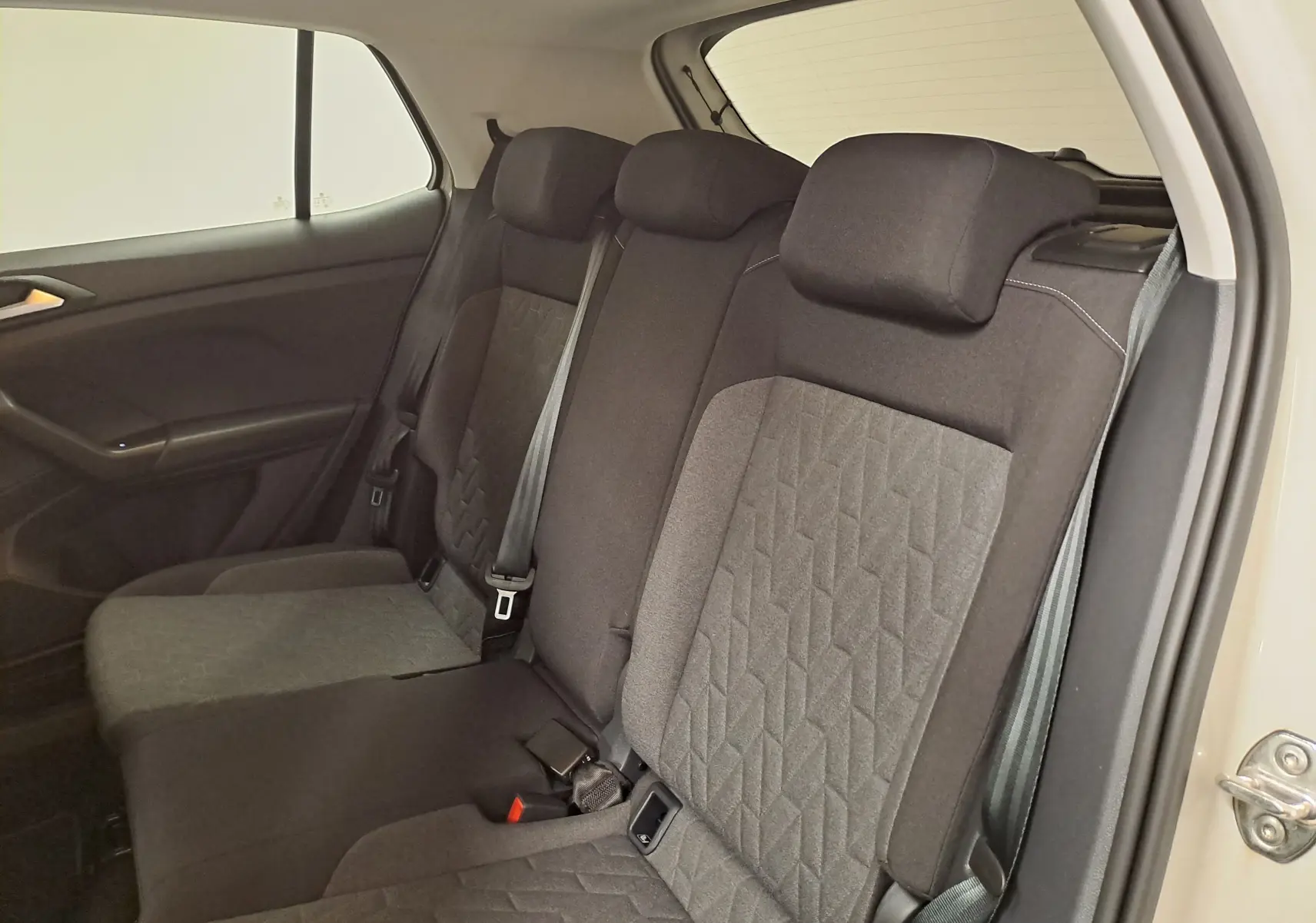 Vue intérieure des sièges arrière en tissu gris du Volkswagen T-Cross 2024, côté droit avec ceinture de sécurité visible.