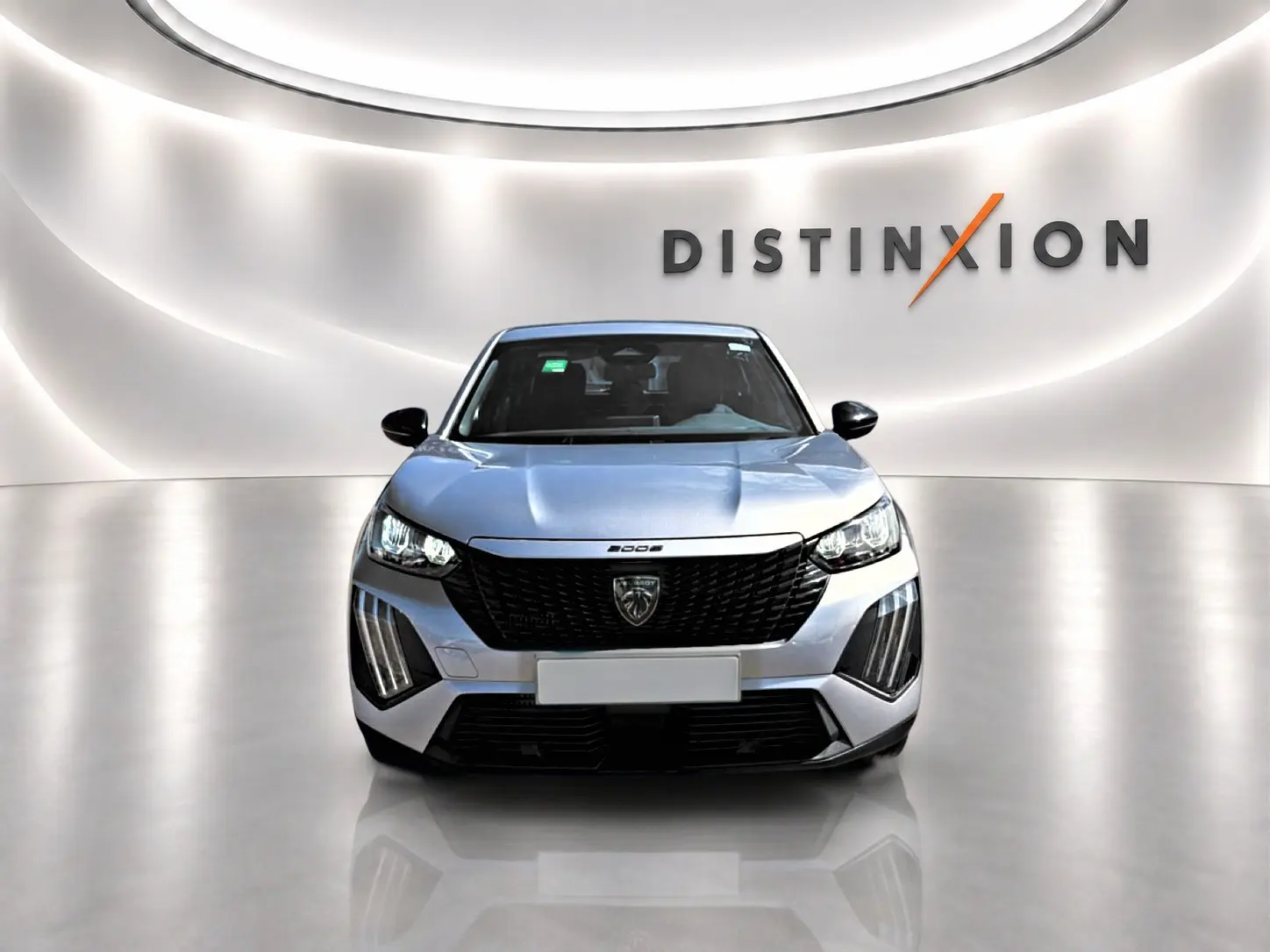 Vue frontale d'un Peugeot 2008 gris 2025 avec calandre noire et feux LED, dans un showroom lumineux.