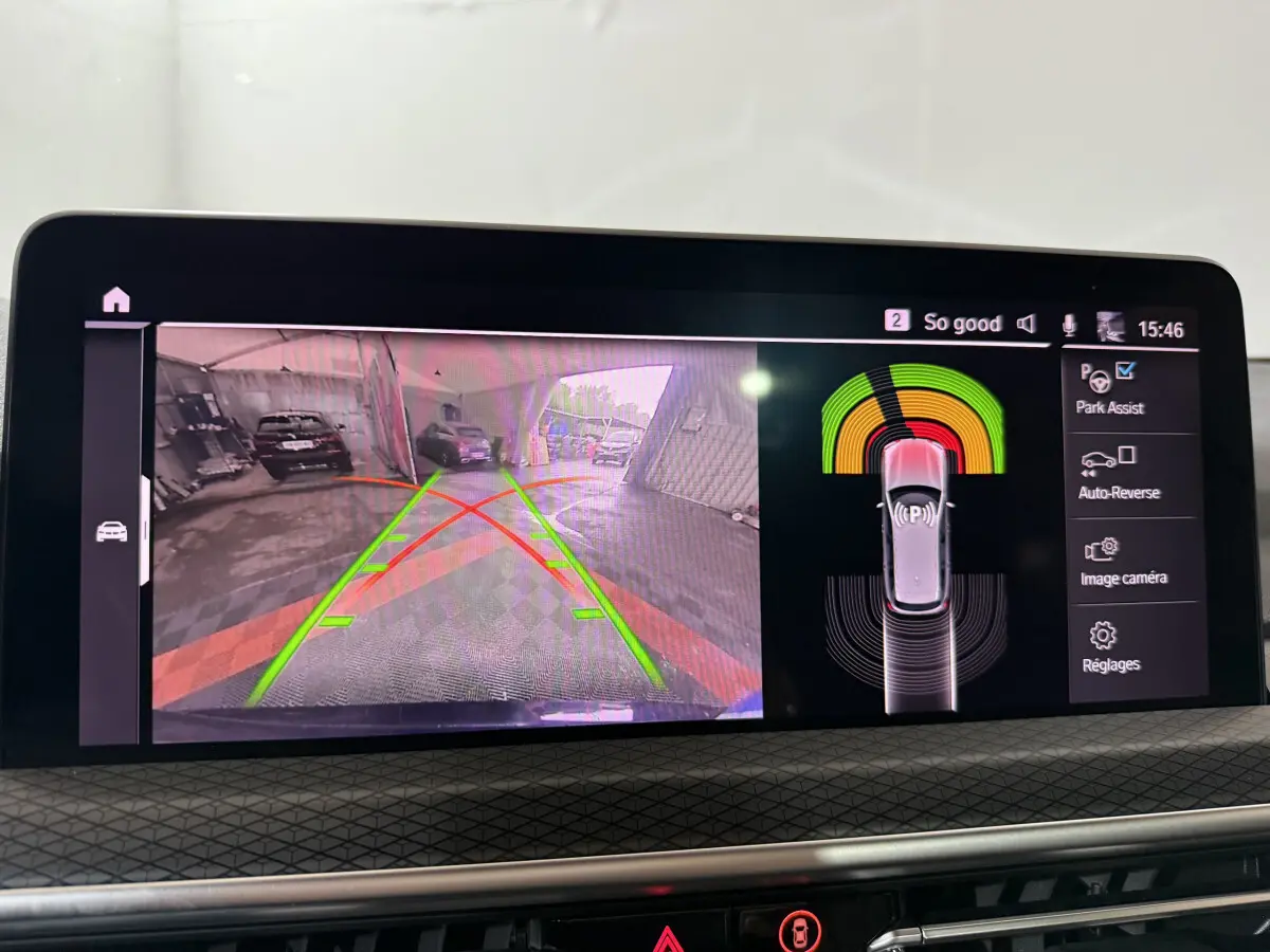 Écran central du BMW X3 xDrive30e 2023 montrant l'aide au stationnement arrière avec vue caméra et capteurs actifs.