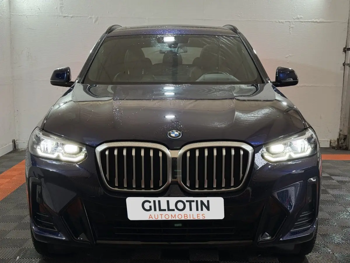 Vue frontale d'un BMW X3 xDrive30e bleu avec phares LED allumés et calandre double haricot caractéristique.