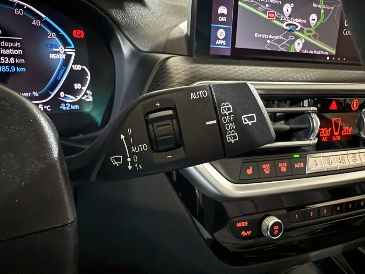 Gros plan sur la commande d'essuie-glace et le tableau de bord numérique d'une BMW X3 xDrive30e bleu 2023, affichage tactile visible.