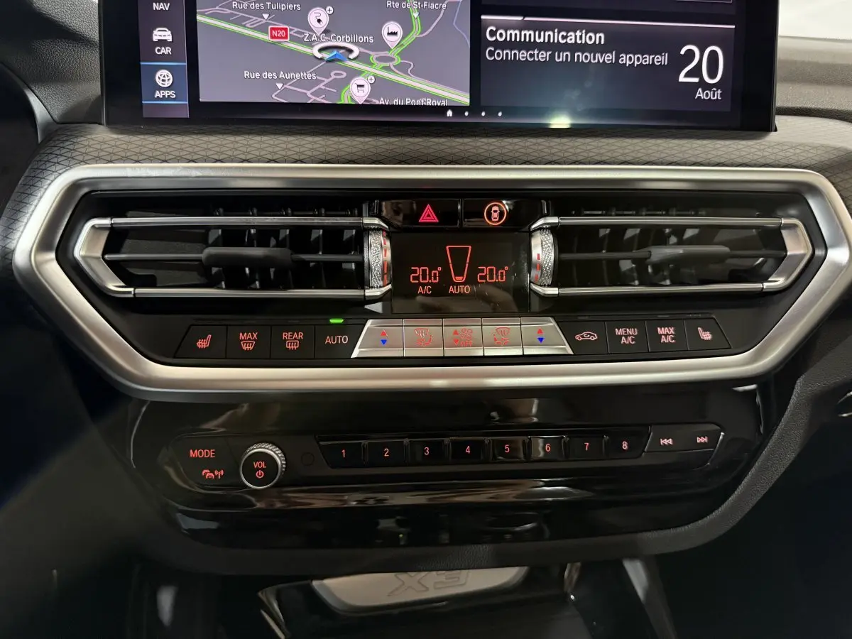 Tableau de bord central du BMW X3 xDrive30e 2023 avec commandes climatisation et écran tactile de navigation.