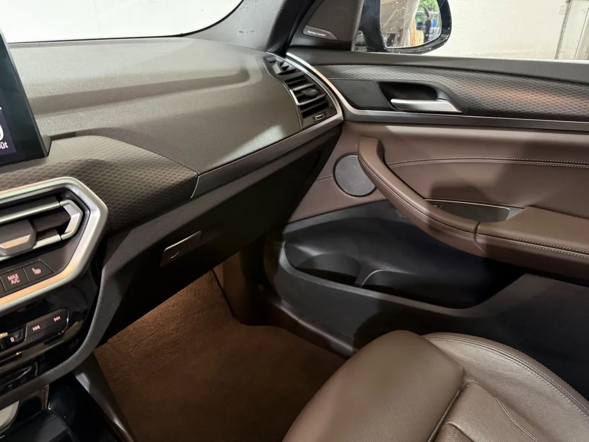 Intérieur côté passager du BMW X3 xDrive30e 2023, avec tableau de bord noir et garniture cuir marron.
