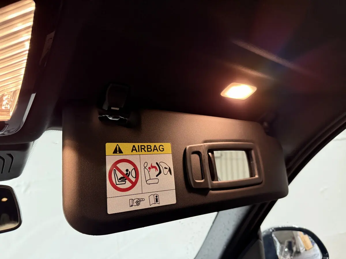 Détail du pare-soleil côté conducteur avec miroir et avertissement airbag dans BMW X3 bleu 2023.