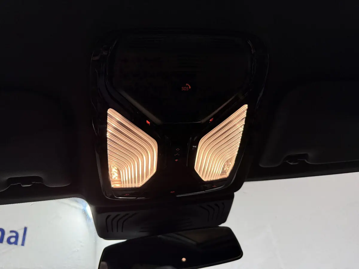 Plafonnier intérieur allumé avec commandes et bouton SOS visible dans un BMW X3 bleu hybride rechargeable 2023.