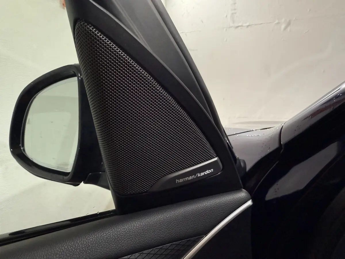 Gros plan sur l'enceinte Harman/Kardon et le rétroviseur côté conducteur d'un BMW X3 bleu 2023.