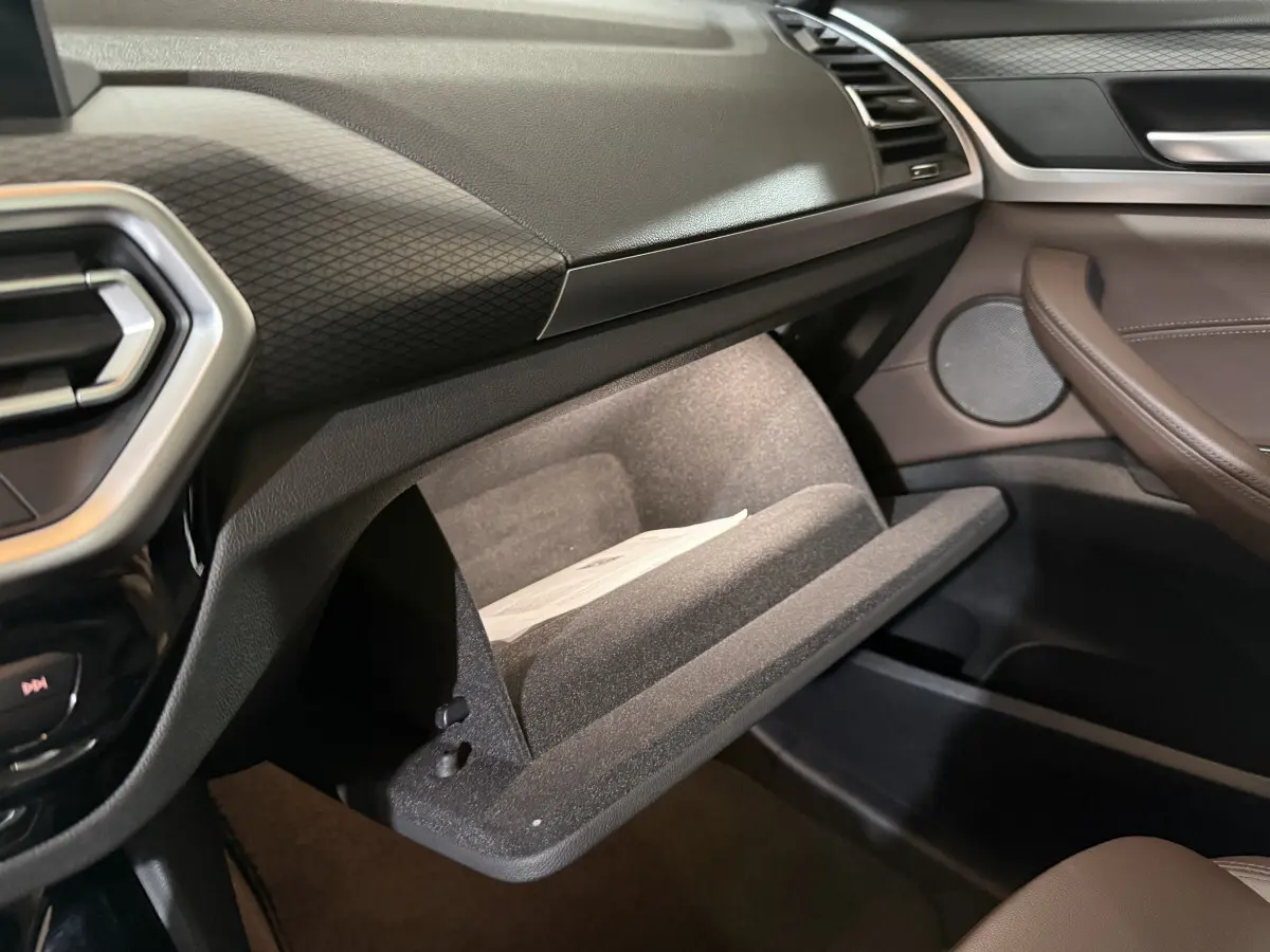 Gant de porte ouvert côté passager dans l'habitacle marron et noir du BMW X3 xDrive30e 2023 M Sport