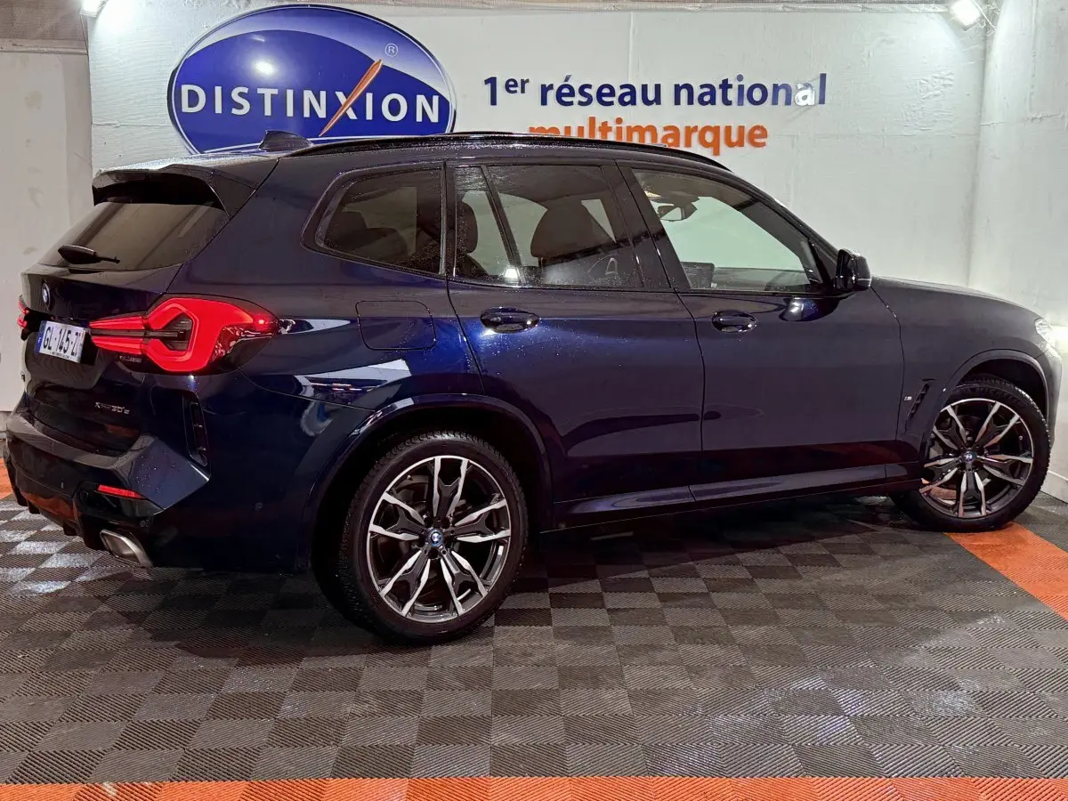 BMW X3 xDrive30e bleu vue de profil côté droit, avec jantes alliage et feux arrière LED distinctifs.